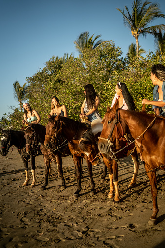 Female friends talking during horseback riding on the beach