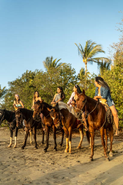 istock Female friends talking during horseback riding on the beach 1489804867