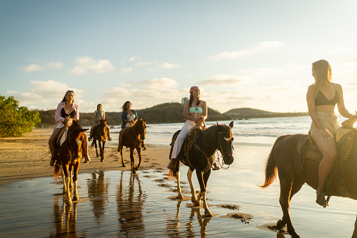 Female friends during horseback riding on the beach