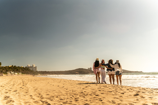 Female friends embracing while walking on the beach