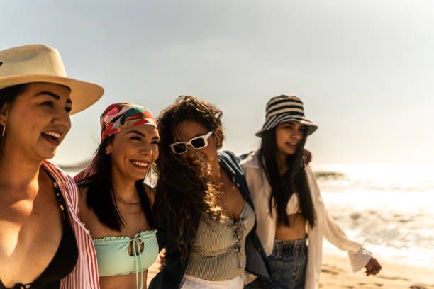 istock Female friends embracing while walking on the beach 1489806836