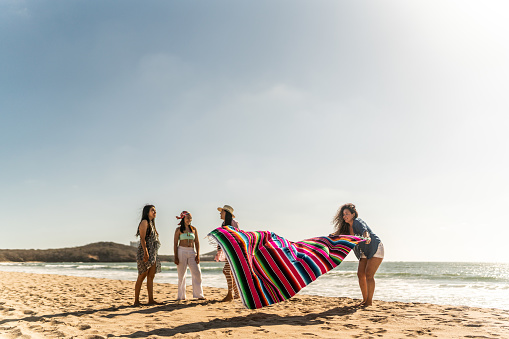 Female friends preparing yoke to sit on the beach