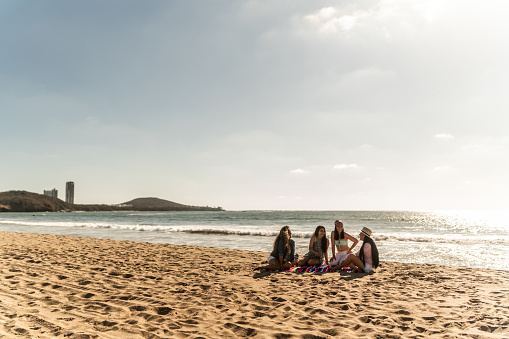 Female friends having a holiday and talking on the beach