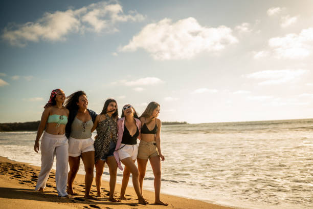 istock Female friends embracing while walking on the beach 1489808038