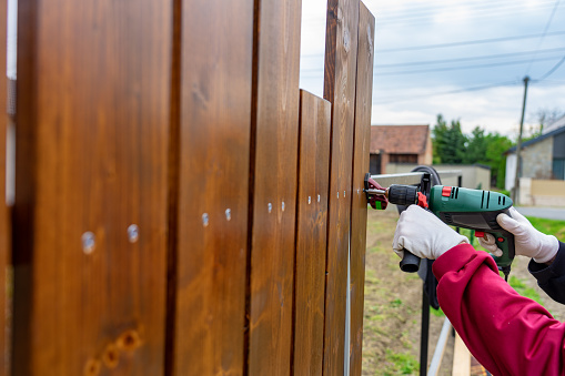 Hombre construyendo su propia cerca de madera especial con perforador photo