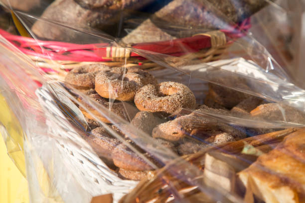 Homemade round biscuits ciambelli with sugar on top packed in white basket with transparent polyethylene film above. Selling sweets in the market. Protective film on food as anti covid measure. . High quality photo