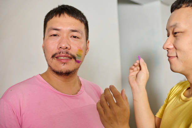 istock Homosexual couple draw rainbow color on their faces. 1489829020