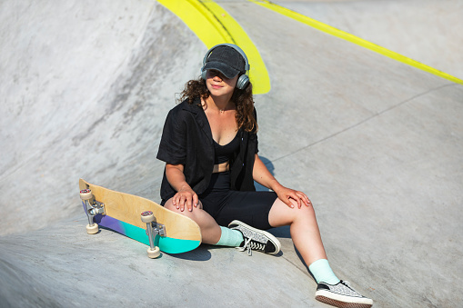 Young adult woman skateboarding in skate park at summer