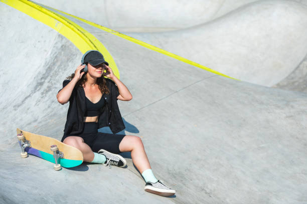 Young adult woman in skate park listening to music stock photo