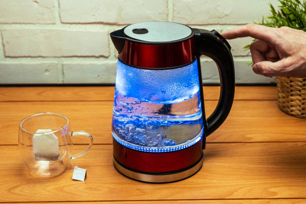 istock man turns off the heating button of a modern glass electric kettle 1489832914