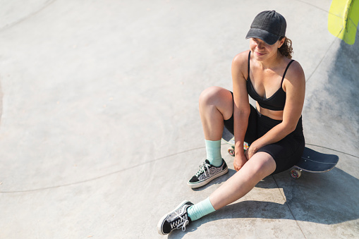 Young adult woman skateboarding in skate park at summer