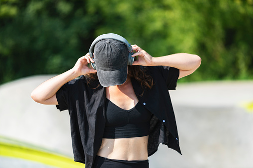 Young adult woman skateboarding in skate park at summer