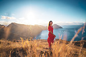 Happy woman in red dress enjoys the morning atmosphere from the foothills of a volcanic island in the Atlantic Ocean. São Lourenço, Madeira Island, Portugal, Europe.
