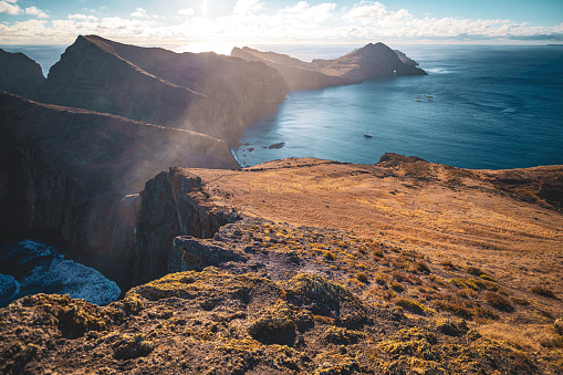 Description: Distant view of tourists hiking on a footpath of a volcanic island in the Atlantic Ocean, in the mornin athmosphere. São Lourenço, Madeira Island, Portugal, Europe.