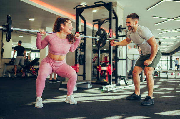istock A happy female bodybuilder is lifting weights with her trainer in a gym. 1489838338