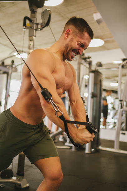 istock A shirtless muscular weightlifter is pulling on a cable machine with a big effort. 1489838343