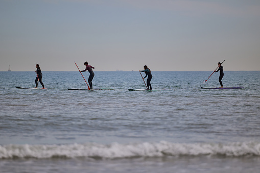 Stand up paddle boarding in the Mediterranean. 4 people practice along the Malvarosа beach of Valencia.