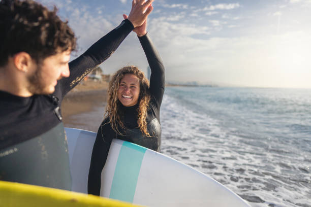 istock Woman interchange high-five with her male surf instructor, after surf lesson 1489850234