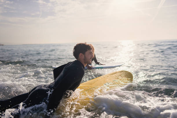 Woman observing her male surf instructor while he trying to catch a wave stock photo