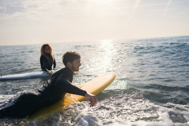 istock Woman observing her male surf instructor while he trying to catch a wave 1489850370