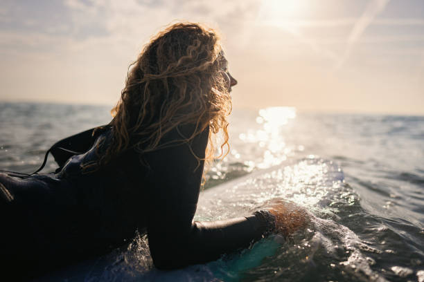 istock Caucasian female surfer swimming with surfboard while trying to catch a wave 1489850382