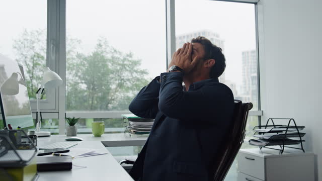 Upset man calling mobile at office workplace. Stressed manager thinking problems