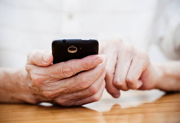 alter mann mit smart phone - palms together stock-fotos und bilder