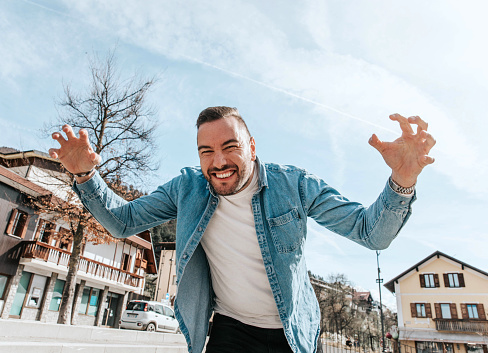 Portrait of a handsome hipster smiling man in a jean jacket. A man in a big city on the street, a life style concept