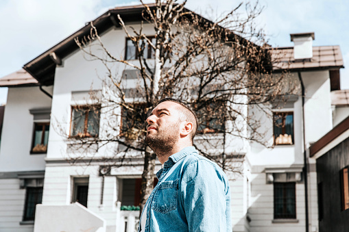 Portrait of a handsome hipster smiling man in a jean jacket. A man in a big city on the street, a life style concept