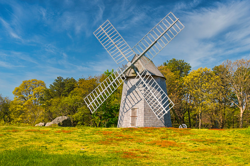 Springtime colors emerge from blooming trees behind the old Higgins Family Windmill in Brewster, Massachusetts on a bright May morning.