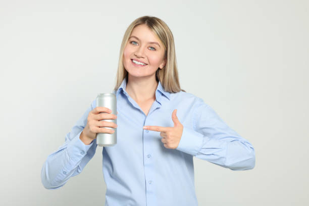 istock Beautiful happy woman holding beverage can on light background 1489905407