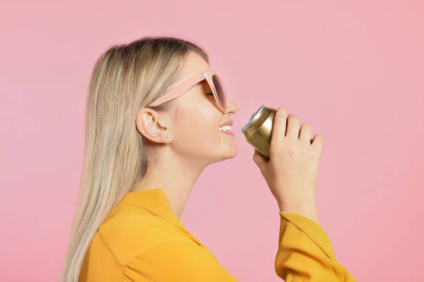 beautiful happy woman drinking from beverage can on pink background - blikje drinken fotos stockfoto's en -beelden