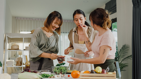 Young Asian women friends preparing vegetarian and cooking salad in kitchen table at home. Lifestyle healthy food eating enjoying natural life and plant-based diet concept.
