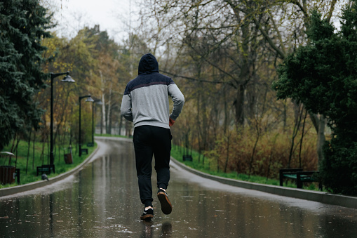 Jogging in the Rain A Physical Challenge for Young Adults. A determined young athlete jogging in the rain, pushing himself physically and mentally