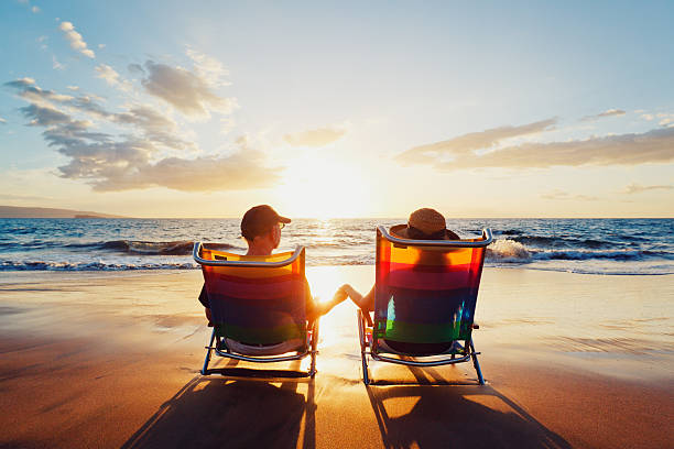 istock A couple, in beach chairs, holding hands at sunset 148992908