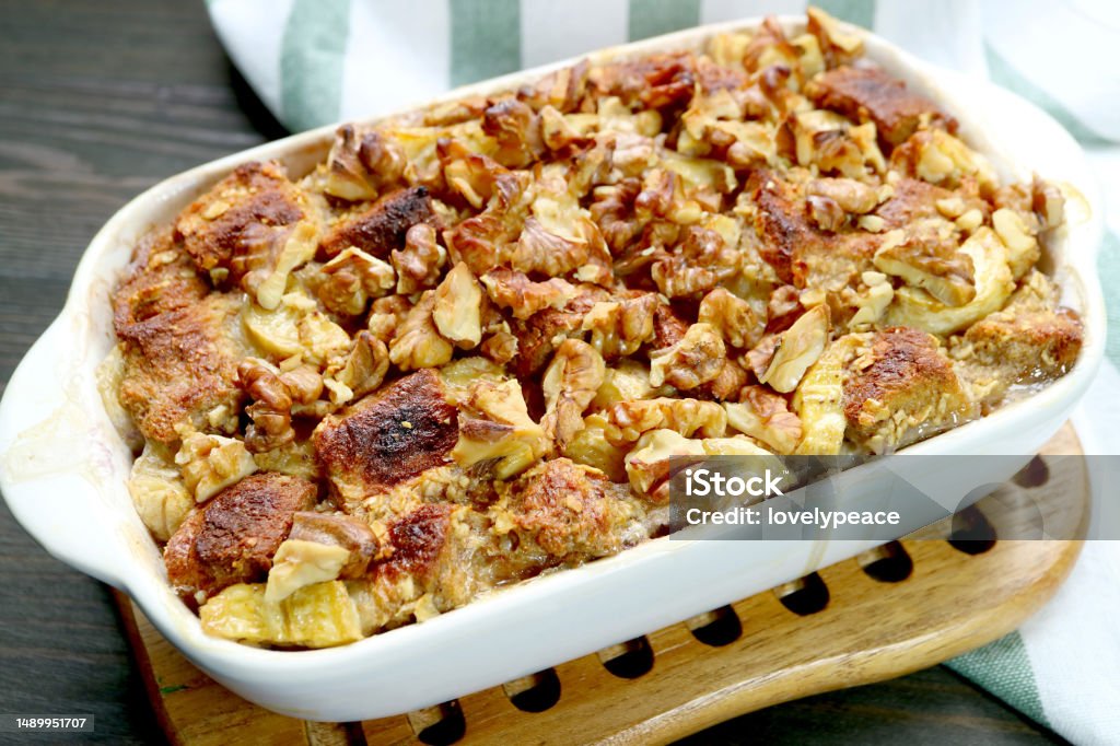 Bowl of Freshly Baked Delectable Banana Walnut Bread Pudding on a Wooden Breadboard Baked Stock Photo