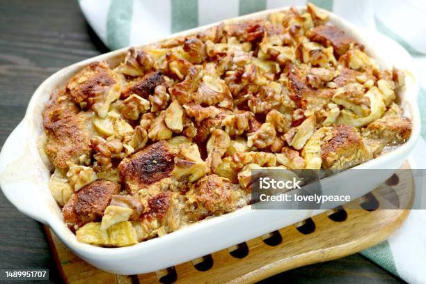 Bowl Of Freshly Baked Delectable Banana Walnut Bread Pudding On A Wooden Breadboard Stock Photo - Download Image Now