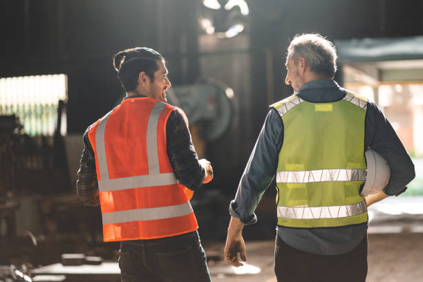 istock Teamwork men in construction site, Two civil engineer or professional foreman in safety helmet hard hat using blueprint in digital tablet working while standing at industrial factory, teamwork concept 1489960427