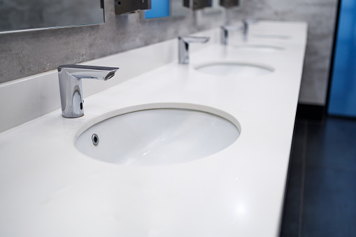 water faucet automatic, white ceramic surface in a public toilet. shared toilet modern washstand