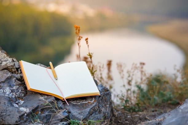 istock an open paper diary is located on a large stone next to the grass on a cliff, the background is blurred outside the forest and the river 1489966650