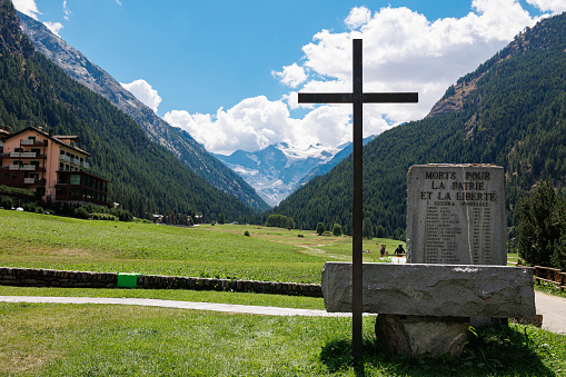 Aosta, Italy - august 2022: Stone Monument with Catholic Cross to the War Victims of the World Wars in Cogne, Aosta - Italy.