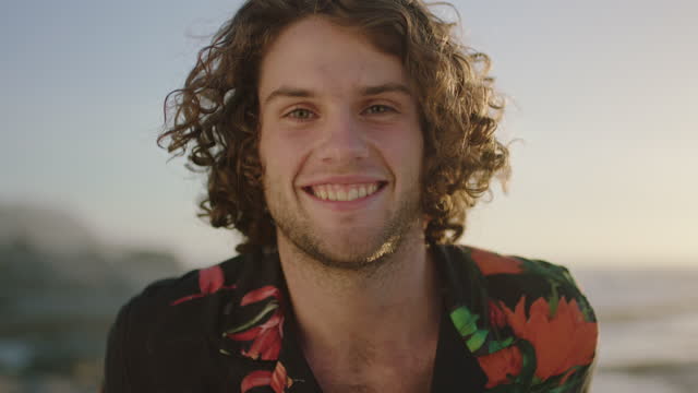 close up portrait of attractive young man smiling cheerful  wearing aloha shirt at sunset