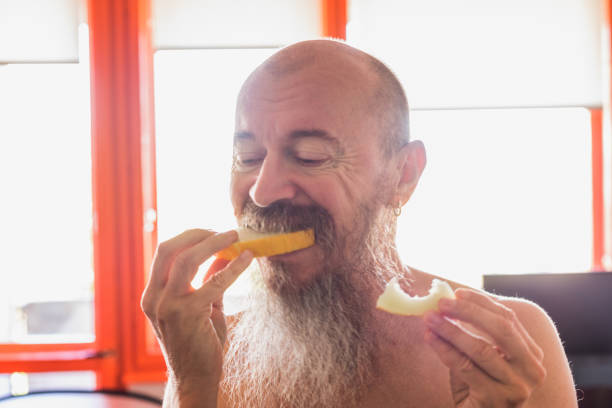 istock Mid adult cool guy with long beard eating melon 1489969364