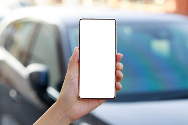 a young asian businesswoman walks to her car while using her smartphone. smartphone with blank screen for design mockup. - fazendo sinal com a mão imagens e fotografias de stock