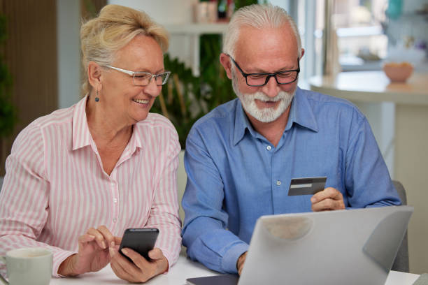 istock Excited and happy elderly couple shopping online from home using computer, smartphone and credit card. Modern technologies and retirement concept. 1489971645