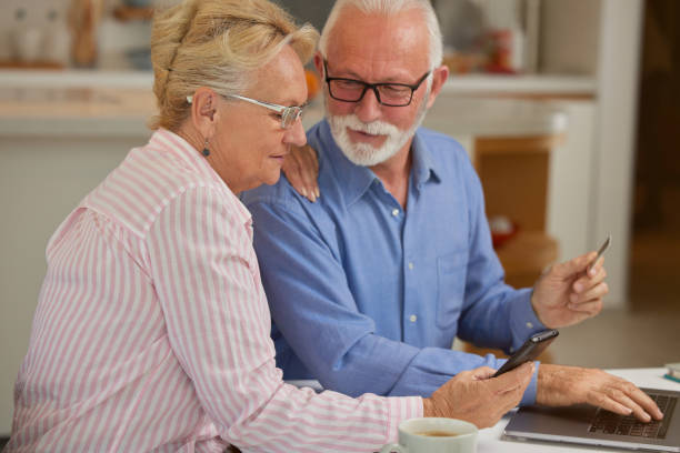 istock Excited and happy elderly couple shopping online from home using computer, smartphone and credit card. Modern technologies and retirement concept. 1489971731