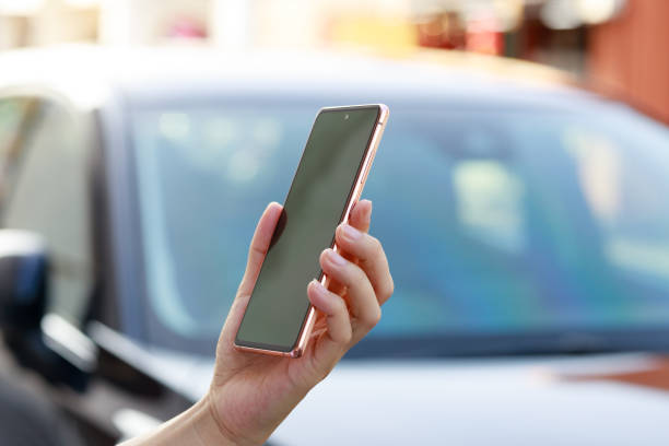 A young Asian woman is ordering a taxi ride and waiting for it using a mobile app on her smartphone