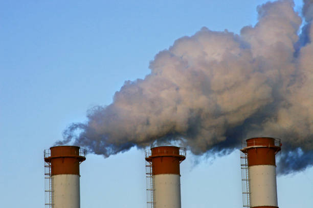 istock Industrial chimneys with white smoke against blue sky. 1489978619