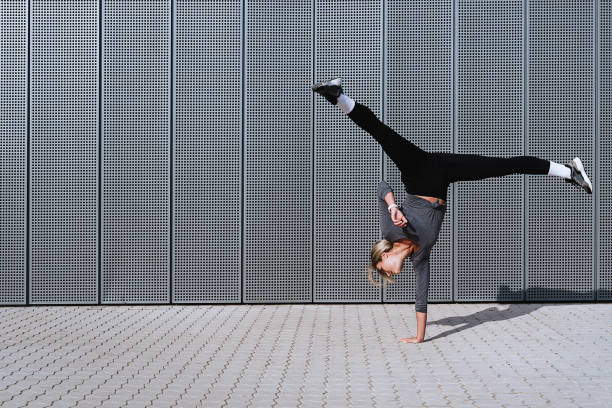 athlète féminine portant des vêtements de sport féminins faisant un mouvement de roue de charrette dans la rue - gymnastique roue photos et images de collection