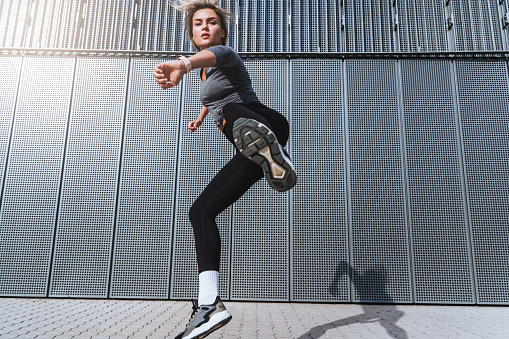 Woman athlete jumping during her high-intensity interval training on the street.